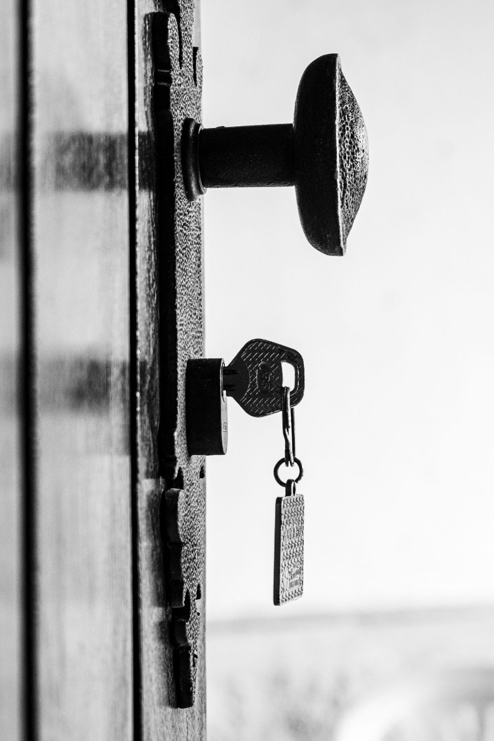 Bouton de porte et clé engagée dans une serrure ancienne, photographie en noir et blanc